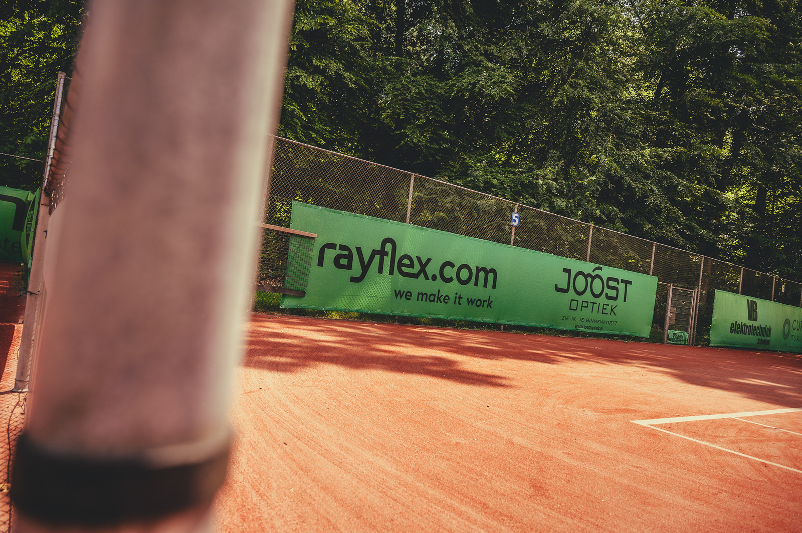 Het rayflex.com-sponsordoek langs de gravelbaan van TC Park Braband, foto door Thijs Blom
