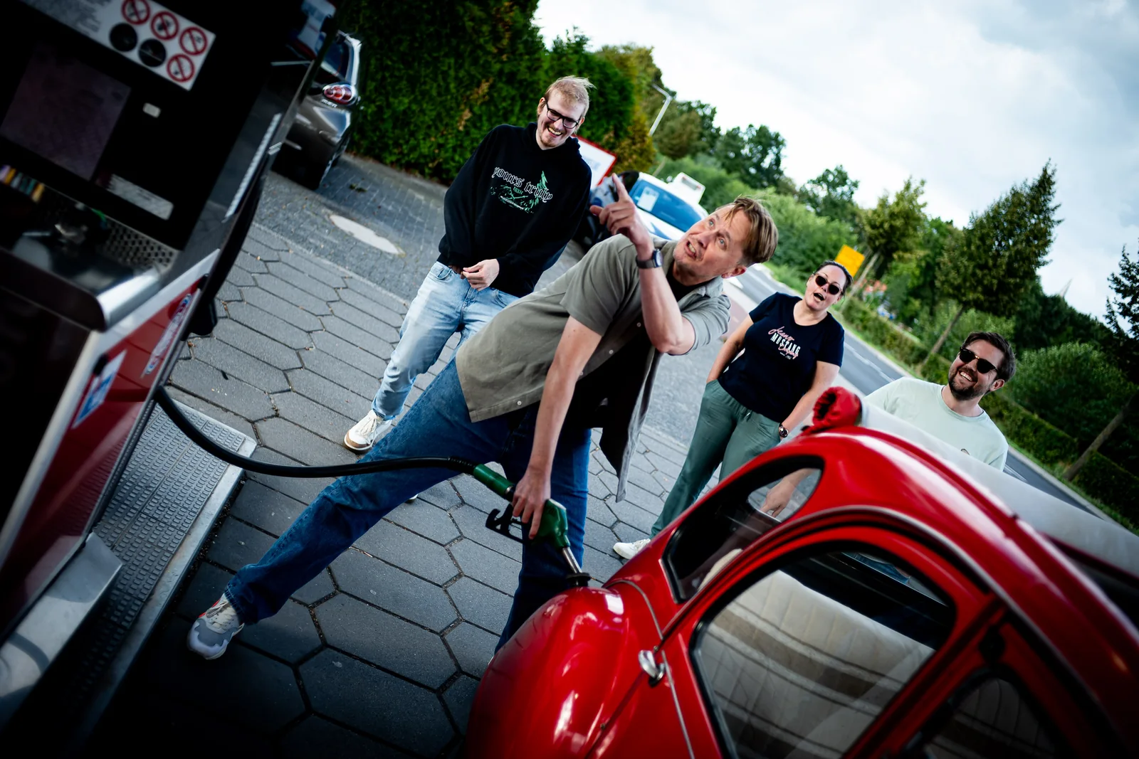 Het team lacht en geeft commentaar terwijl er getankt wordt, foto door Raymond Rothengatter